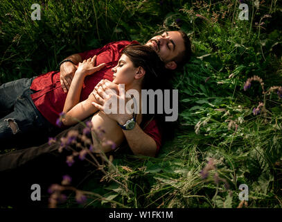 Un jeune couple est allongé et se reposant dans un pré parmi les fleurs sauvages. Vue d'en haut. Banque D'Images