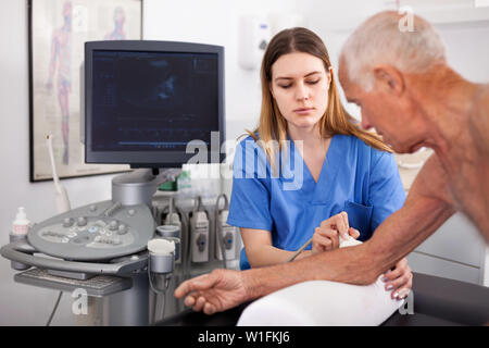 Friendly diligent female male patient diagnostic technicien en utilisant l'échographie modernes en clinique privée Banque D'Images