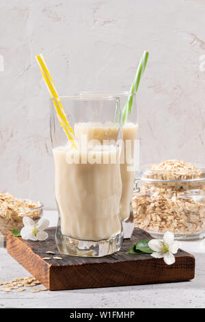 Deux figuré en bonne santé avec des verres de lait d'avoine sur marron brûlé et pot de flocons oaty sur fond clair. Banque D'Images