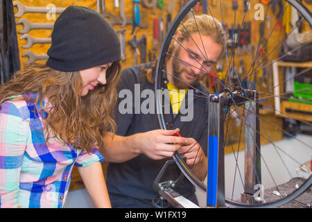 Bel beraded guy et la jolie fille la réparation de vélo dans l'ensemble de l'atelier Banque D'Images