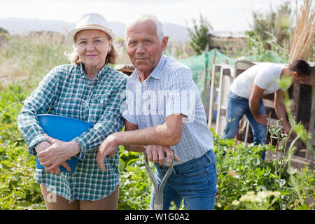 L'homme et la femme des jardiniers avec pelle et godet tout en faisant du jardinage dans un jardin extérieur de Banque D'Images