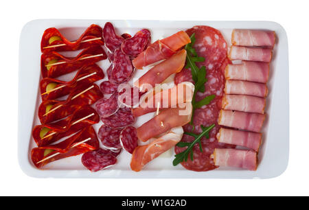 Vue de dessus de viandes froides fraîches de l'espagnol salaison à sec jamon, piquante saucisses et bacon garnie avec des verts et les olives sur plaque rectangulaire. Isolated over white Banque D'Images