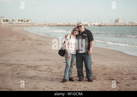 Happy senior couple enjoying de vie à la retraite s'amusant de marcher sur la plage dans une belle journée ensoleillée se tenant la main et serrant les uns les autres tout en Banque D'Images