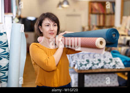 Vendeuse expérimentée organisant les vis en tissu boutique textile, préparation à la vente Banque D'Images