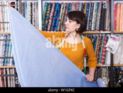 Vendeuse compétente a ordonné de mesure pour la coupe de tissu textile en boutique, la préparation pour la vente Banque D'Images