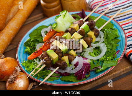 Foie de poulet grillées brochettes de coeurs avec avocat mûr, servi avec des feuilles de salades et concombres Banque D'Images