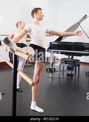 Chorégraphe femme et jeune homme de faire les exercices à la barre de ballet dans le hall avec miroir Banque D'Images