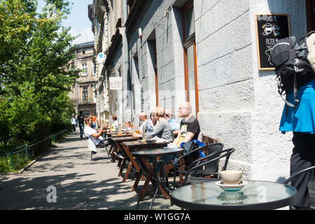 Touristes profitant du soleil à l'extérieur d'un café à Cracovie, Pologne, Europe. Banque D'Images