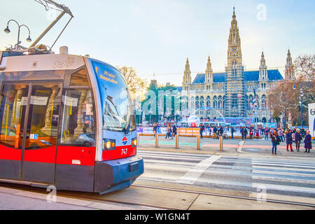 Vienne, Autriche - 18 février 2019 : Le tramway moderne rides le long de la Ringstrasse, passant Rathausplatz avec anneau de patinage en hiver et belle mairie, o Banque D'Images