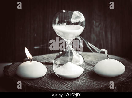 Le temps presse, la vie et la mort. Une bougie brûle avec une flamme, d'autres vivant est repoussée, comme mort et vie. mesures hourglass Banque D'Images