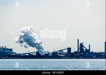 HAMILTON, CANADA - 21 avril 2018 : un grand panache de vapeur est à la dérive est libéré à une usine d'acier sur la rive du port de Hamilton. Banque D'Images