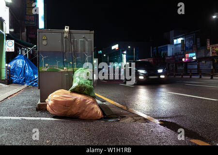 Séoul, Corée du Sud - 30.10.18 : Les sacs de déchets se trouvent sur le côté de la route de nuit. un tas d'ordures jetées sur la route. de néons. p l'environnement Banque D'Images