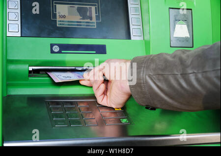 La main d'un homme est de l'argent dans un guichet automatique takeing. Banque D'Images