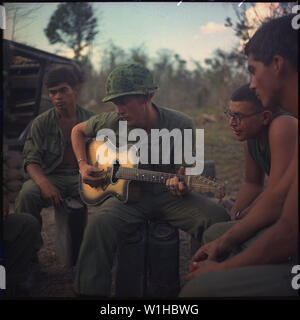 YELLOWSTONE OPÉRATION VIETNAM : Après une dure journée, quelques membres de la Compagnie A, 3e Bataillon, 22e Infanterie (mécanisé), 25e Division d'infanterie, se réunir autour d'un joueur de guitare et chanter quelques chansons. Banque D'Images