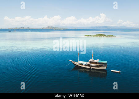 Bateau de croisière de luxe à proximité de l'île de l'atoll de corail blanc avec une plage tropicale et les montagnes à l'horizon. Vue aérienne. Voyage maritime de luxe Banque D'Images