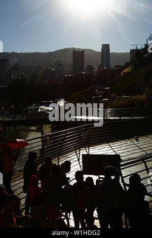 La Paz, Bolivie 2 Juillet 2019 : Les gens d'utiliser la file d'un télescope pour regarder une éclipse partielle du soleil à regarder une éclipse événement près du centre-ville. À La Paz l'éclipse a duré environ 2 heures 10 minutes avec environ 55 % de couverture à son maximum. Le gratte-ciel à droite du centre est le nouveau Palais Présidentiel / Casa Grande del Pueblo. Banque D'Images