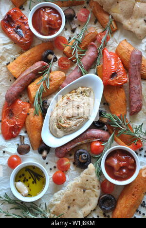 Saucisses grillées et légumes Plateau servi avec pain pita, d'humus et de champignons grillés, tomates cerises, patates douces et d'herbes. Barbecue grill Banque D'Images