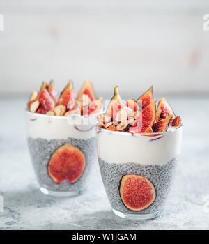 Chia pudding sain avec du yogourt, les figues et les noix dans du verre. Idées et recettes pour petit-déjeuner sain, une collation ou un dessert. En verre avec deux graines chia pudding avec copie espace pour le texte Banque D'Images