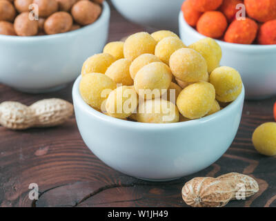 Snack-d'arachide pour la bière, vin, partie bar. Arachides salées au fromage jaune vernis sur table en bois brun. Copier l'espace. Banque D'Images