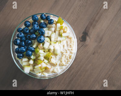 Vue de dessus du bol avec millet bouillie sur fond de table en bois. Porridge de millet bio avec Blueberry et de poire, l'espace de copie pour le texte. Soft focus DOF peu profondes, Banque D'Images