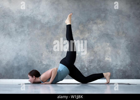 Woman practicing yoga faisant eka pada Shalabhasana, le Criquet des variations de la Banque D'Images