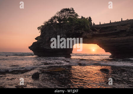 Coucher du soleil au moyen d'une falaise rocheuse sur la mer au coucher du soleil. Pura Batu Bolong, Bali, Indonésie Banque D'Images