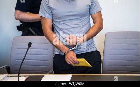 Bad Kreuznach, Allemagne. 06Th Juillet, 2019. Le défendeur est menotté dans la salle d'audience. C'est le début d'un procès contre un demandeur d'asile Afghan de Biblis qui est dit d'avoir poignardé la mère-à-être de l'enfant ensemble. Dans l'acte en janvier de cette année, les 25 ans a été grièvement blessé, l'enfant à naître a été tué. Crédit : Andreas Arnold/dpa/Alamy Live News Banque D'Images