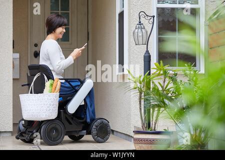 Japanese woman sur fauteuil roulant électrique Banque D'Images