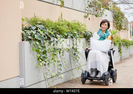 Japanese woman sur fauteuil roulant électrique Banque D'Images