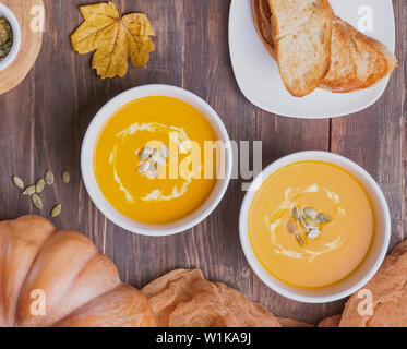 Deux bols de soupe au potiron maison delecious avec de la crème sur la table en bois Vue de dessus Banque D'Images