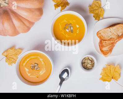 Delecious crème de citrouille maison soupe dans un bol blanc avec des feuilles d'automne sur le fond blanc Vue de dessus Banque D'Images