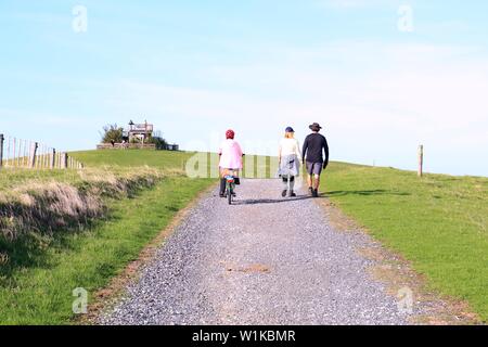 Un cycliste de rouler à vélo et un couple holding hands together marche sur une route - filtre Soft Banque D'Images
