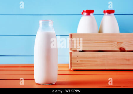 Bouteille de lait en face d'une caisse en bois pleine de bouteilles de lait sur une table de cuisine en bois Banque D'Images