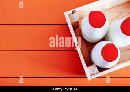 La bouteille de lait traditionnel dans une caisse en bois sur la table de cuisine en bois d'orange. Vue de dessus avec l'exemplaire de l'espace. Banque D'Images
