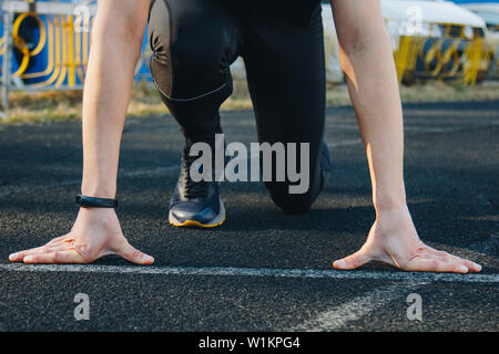 Un coureur sur la ligne de départ sur la piste du stade est en attente de départ. Banque D'Images