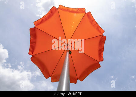 Photo d'un parasol sur le ciel bleu,parasol.Une couleur orange vif, parasol contre ciel bleu vif et blanc nuage. Banque D'Images