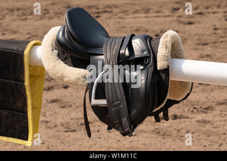 Description : selle anglaise et la patte d'accroché sur une porte de l'écurie en bois Banque D'Images