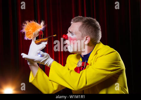 Clown de cirque effectue nombre. Un homme dans un costume de clown avec un jouet Banque D'Images