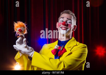 Clown de cirque effectue nombre. Un homme dans un costume de clown avec un jouet Banque D'Images