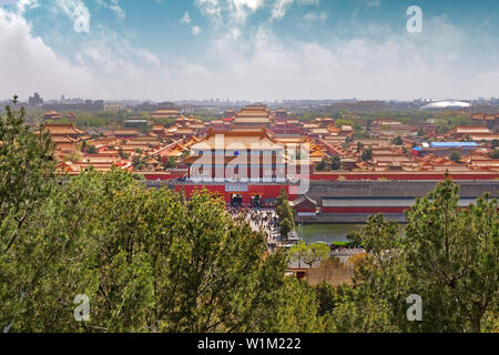 Vue sur les toits rouges et orange et les murs du musée du palais à Pékin, Chine, couvert par des nuages blancs sur un ciel bleu, et le paysage urbain dans le background Banque D'Images