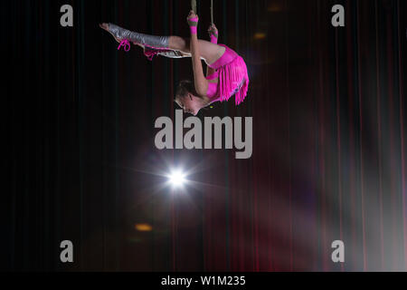 Artiste de cirque acrobat performances. La jeune fille effectue des éléments acrobatiques dans l'air. Gymnaste de cirque sur la scène Banque D'Images