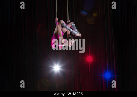 Artiste de cirque acrobat performances. La jeune fille effectue des éléments acrobatiques dans l'air. Gymnaste de cirque sur la scène Banque D'Images