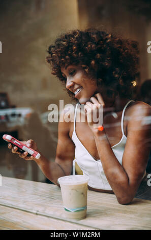 Jolie femme de prendre un verre dans un café, vue à travers l'écran Banque D'Images