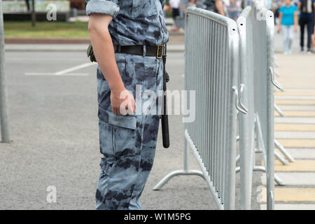 Description : Un policier avec un bâton près de la clôture métallique, close-up Banque D'Images