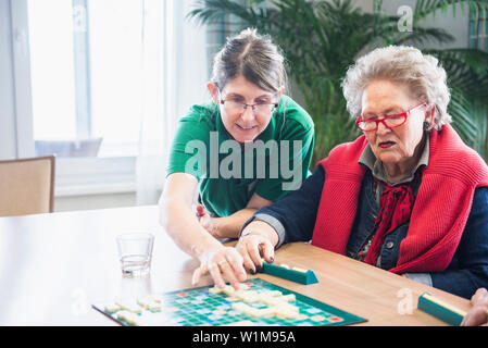 Aider le personnel infirmier senior couple jeu de scrabble Banque D'Images