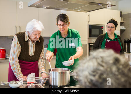 Aider le personnel infirmier senior woman cooking in rest home Banque D'Images