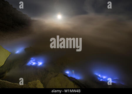 Soufre brûlant avec des flammes bleues du volcan Ijen de nuit avec la pleine lune et les étoiles, l'Est de Java, Indonésie, volcan Ijen Banque D'Images