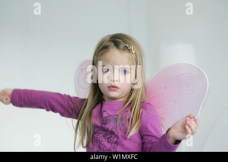 Girl (3-4 ans) portant des ailes de papillon holding baguette, Munich, Allemagne Banque D'Images