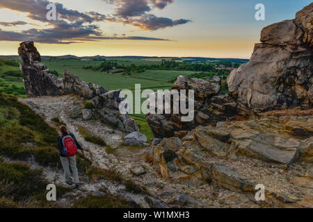 Jeune femme est la randonnée le long du mur de la formation rocheuse Teufelsmauer (Diable) au coucher du soleil, Neinstedt, Thale, résine avant-pays, montagnes du Harz (Saxe-Anhalt), Germ Banque D'Images