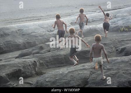 Des enfants jouer et courir à travers le champ de cendres au pied du volcan Tavurvur, Papouasie-Nouvelle-Guinée, New Britain, Pacifique Sud Banque D'Images